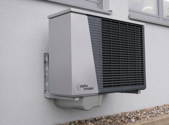 Heat pump outdoor unit mounted on a white residential wall