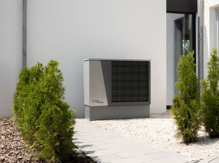 Modern heat pump unit installed beside a residential home with landscaping