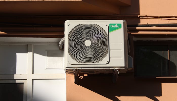 Residential air conditioning condenser unit mounted on a building exterior wall